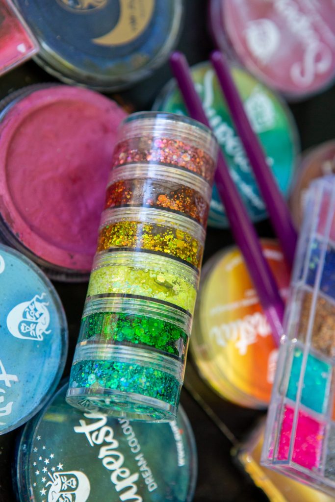 Detailaufnahme von Gesichtsglitzerpaste neben professionellen Theaterschminkfarben