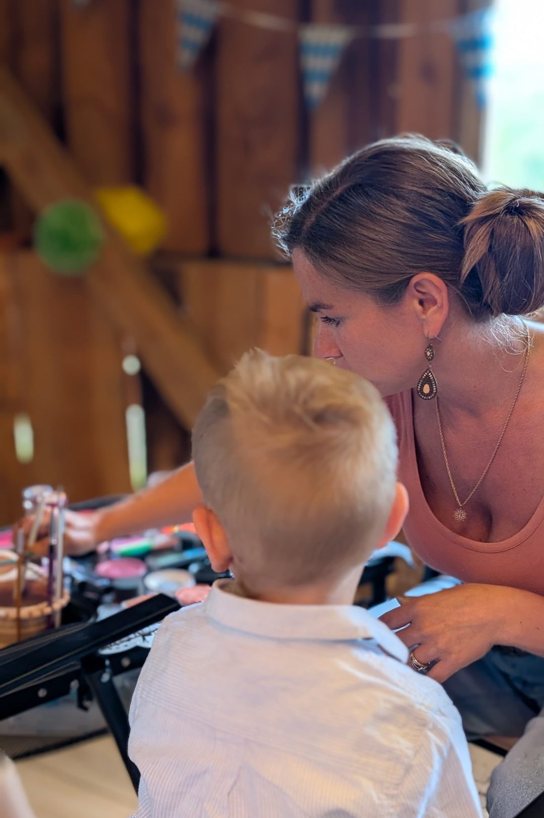 Kinderschminkerin bemalt das Gesicht eines Kindes bei einer Indoor-Veranstaltung